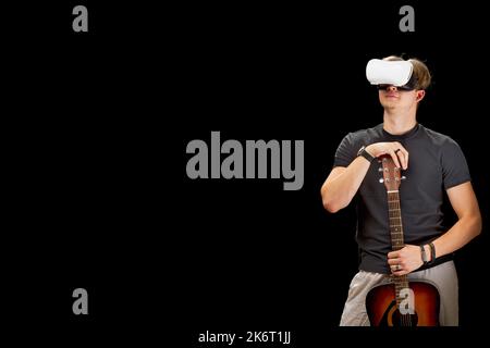Man playing guitar game in virtual reality helmet. VR goggles, glasses, on black isolated background Stock Photo