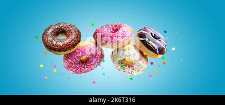 Flying glazed Various donuts over blue background. Stock Photo