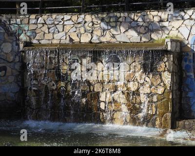 artificial waterfall in a forest park in summer. Vacation concept Stock Photo