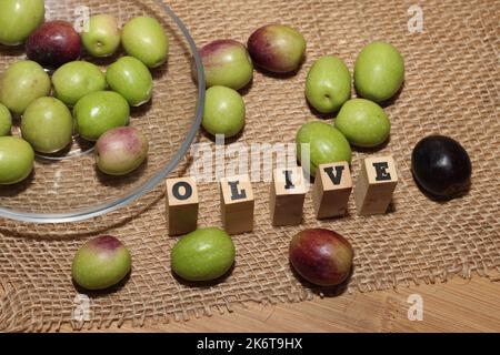 Olives and Olive Oil on wooden background Stock Photo