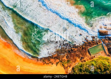 Whale beach rock pool on Sydney Northern beaches Pacific coast in soft morning sun - aerial top down view. Stock Photo