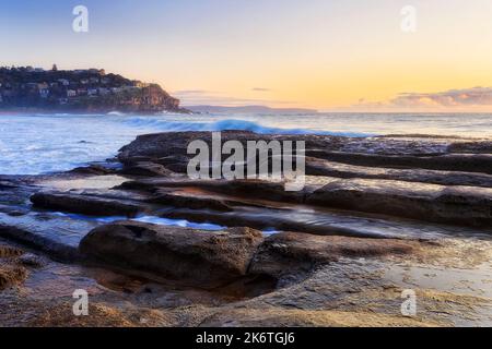 Eroded sandstoen rocks on Whale beach of Sydney Pacific coast in view of Little head walthy suburb of Northern beaches. Stock Photo