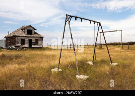 Abandoned swing set in the playground of the public school at the ghost town of Robsart, Saskatchewan. Stock Photo