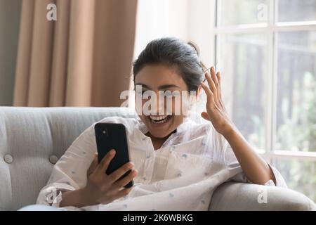 Overjoyed Indian woman staring at cellphone screen read fantastic news Stock Photo
