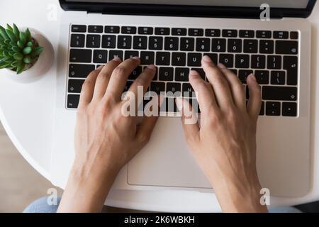 Unknown female hands typing message using laptop keyboard, top view Stock Photo