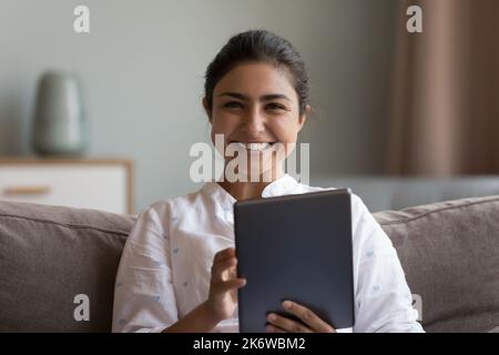 Happy Indian woman using digital tablet smile staring at camera Stock Photo