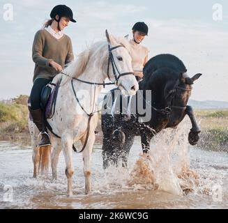 Horses like putting on a show too. two young women out horseback riding together. Stock Photo