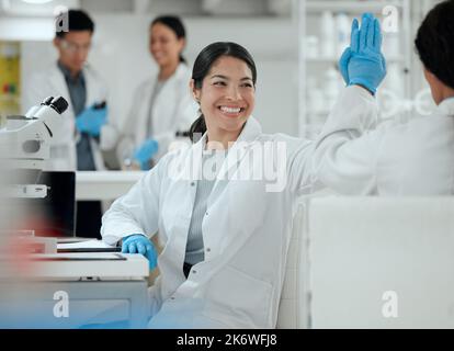 Spreading the love around. two scientists high fiving one another. Stock Photo