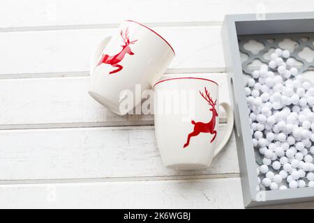 Two white coffee cups with a Christmas deer pattern. Beautiful holiday glass cups Stock Photo