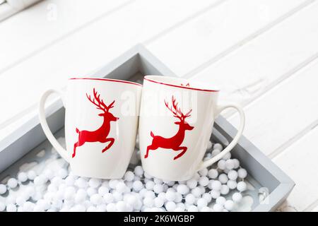 Two white coffee cups with a Christmas deer pattern. Beautiful holiday glass cups Stock Photo