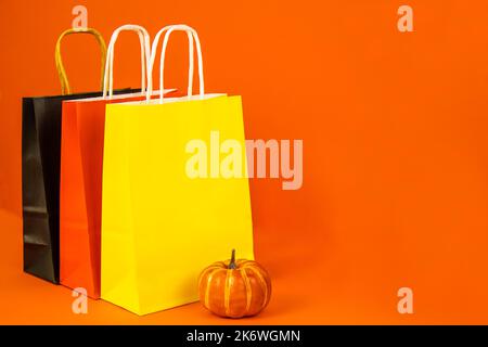 Paper bags yellow, red, black and pumpkin on an orange background. Banner  Stock Photo