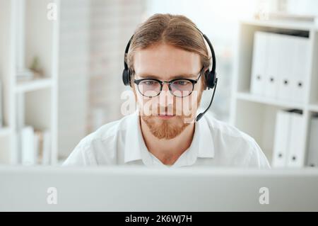 On the search for a solution. a handsome young male call center agent working at his desk in the office. Stock Photo