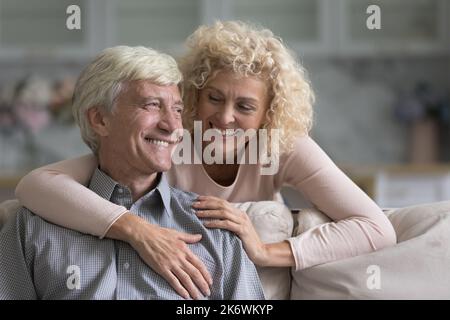 Older smiling wife hugs her beloved cheerful husband Stock Photo