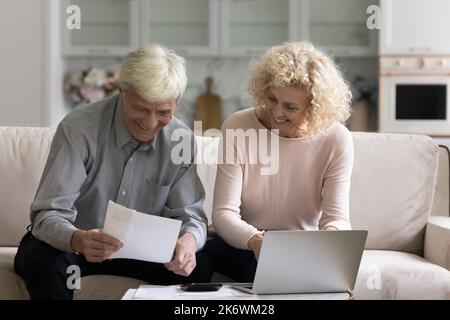 Older couple feel satisfied by enough money paying monthly bills Stock Photo