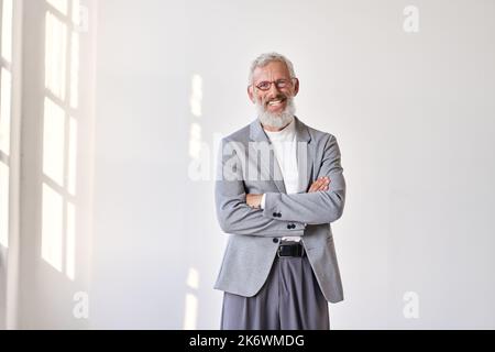 Happy senior older business man wearing suit standing isolated on white wall. Stock Photo
