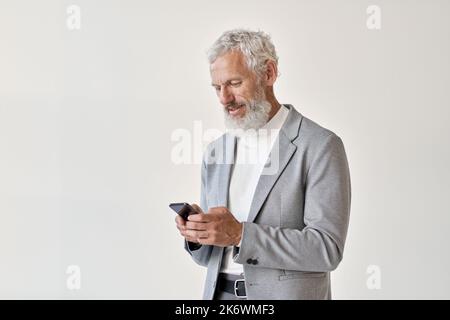 Old senior business man using smartphone standing isolated on white. Stock Photo