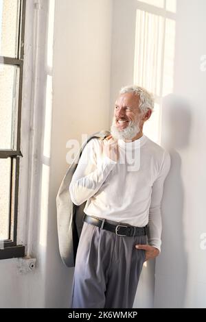 Smiling stylish senior older business man looking through window. Stock Photo