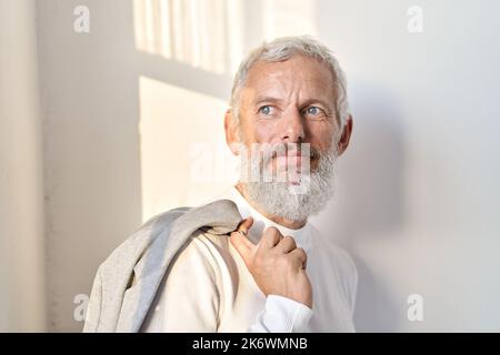 Thoughtful stylish senior older business man looking through window. Stock Photo
