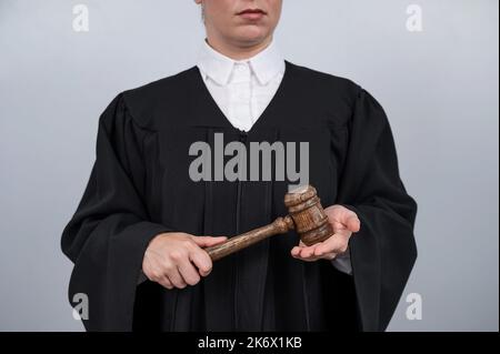 Faceless female judge in a robe holding a court gavel.  Stock Photo