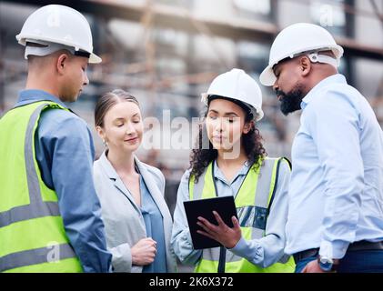 Theyre the right team for the job. a group of architects using a digital tablet at a building site. Stock Photo