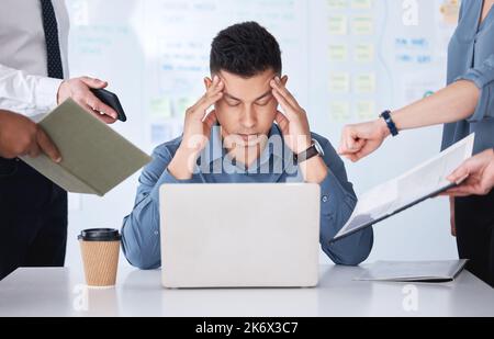 Stressed mixed race businessman being nagged by colleagues. Irritated and annoyed hispanic professional man feeling frustrated and suffering from a Stock Photo