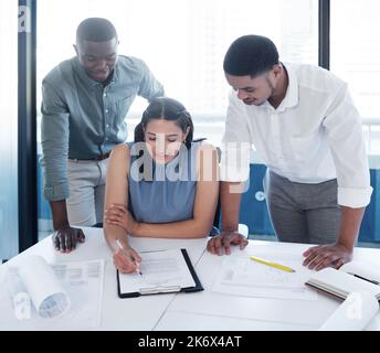 Some adjustments need to be made. a team of young architects drawing up blueprints together. Stock Photo