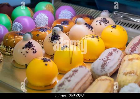 Set of multicolor mousse cakes and eclairs on counter at food market Stock Photo