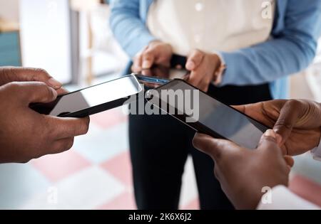 Connected through the world wide web. a group of unrecognisable businesspeople using their smartphones in a modern office. Stock Photo