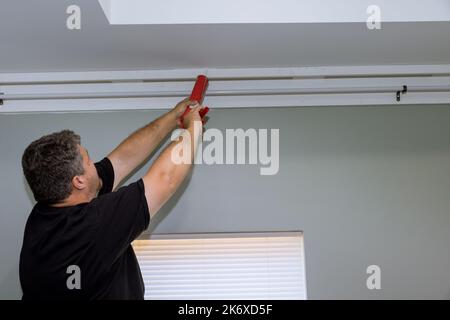 An acrylic sealant is injected into seam between cornice and ceiling using syringe used by construction worker Stock Photo