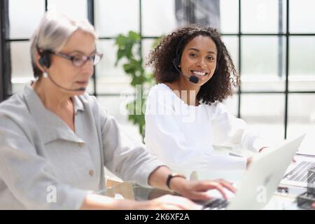 Young friendly operator woman agent with headsets working in a call centre. Stock Photo
