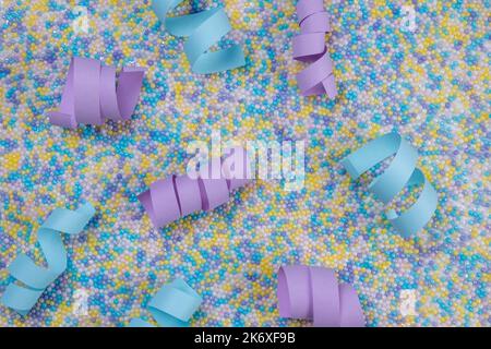 Festive multi-colored background in pastel delicate colors with sprinkles for cake and blue and purple serpentine or ribbons.  Stock Photo