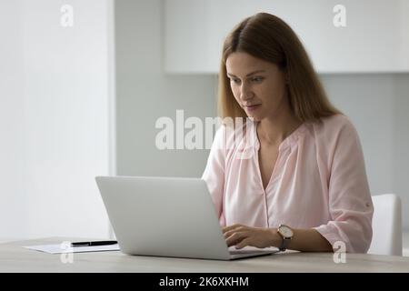 Business lady working on laptop in domestic kitchen Stock Photo
