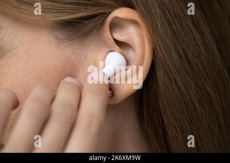 Woman wear wireless earphone, close up cropped female shot view Stock Photo