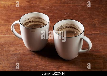 Two cups of brewed coffee milk on a wooden rustic table Stock Photo