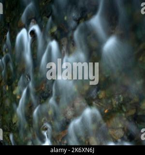 A long camera exposure blurs the surface of the fast-flowing Valira del Nord river as it tumbles over rocks and riverbed pebbles in the Coll d’Ordino, a beautiful eastern Pyrenees valley in northern Andorra.  Square format image captured beside the Pont d’Ordino or Pont de l’Estarell, an ancient humpback bridge spanning the river just north of the hamlet of Llorts. Stock Photo