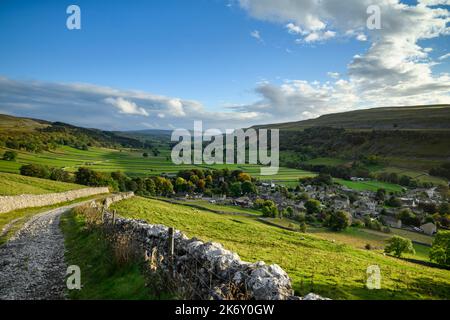 Picturesque Dales view (wide sunlit u-shaped valley, steep hillside slopes, cottages & houses, dramatic blue sky) - Kettlewell, Yorkshire, England UK. Stock Photo