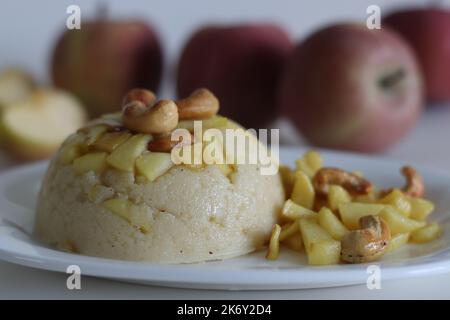 Apple Sheera. Indian pudding made of semolina flour, ghee, milk, dates and dry fruits served with caramelised apple. Classic Indian sweet shot on whit Stock Photo