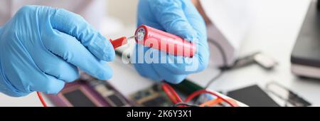 Hands hold a red lithium titanium battery and a voltmeter Stock Photo