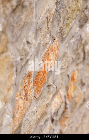 Stone wall. Uneven rough rock surface. Abstract brown background. Vertical view Stock Photo