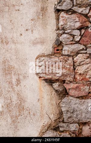 Old stone wall with a cement plastered grunge surface. Copy space. Vertical view Stock Photo