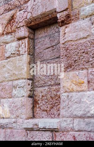 Bricked up window of an old ancient building with uneven stone wall close-up Stock Photo