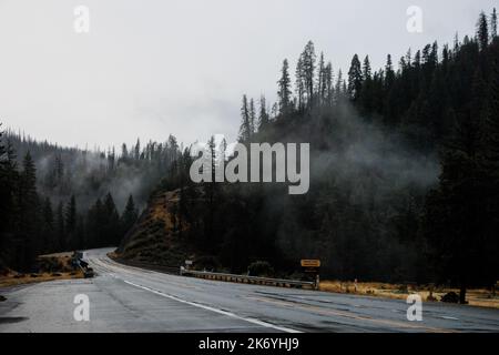 Thin clouds over the empty mountain road in California. Dramatic misty road in the evening Stock Photo