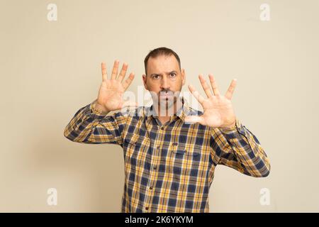 Front view of a Caucasian man with short hair wearing a checkered shirt with his hands palms in front of him, with the camera facing the palm Stock Photo
