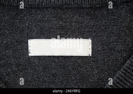 Blank stripe, label for branding on sweater. Tag mockup on gray cloth, top view. Stock Photo