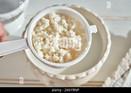 Fresh kefir grains in a white strainer - preparation of homemade fermented drink Stock Photo