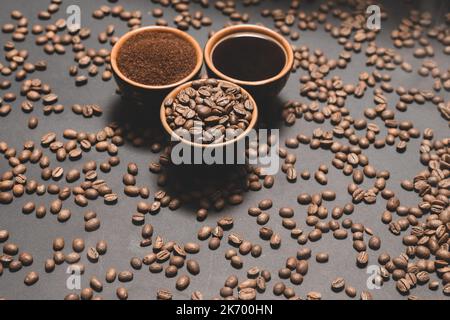 Set of three cups of coffee beans, ground and drink on a black background. Stock Photo