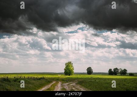 Dramatic Dark Sky On Horizon Above Rural Landscape Meadow. Heavy Rain Clouds Sky Above Grassland. Dramatic Sky With Clouds Above Countryside Rural Stock Photo