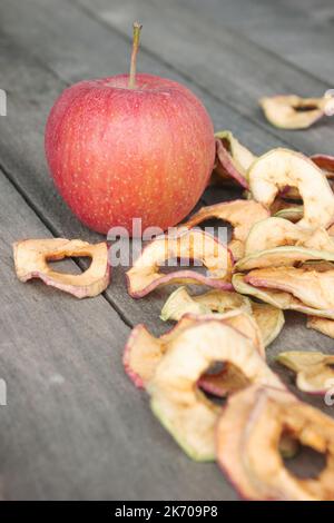 One red apple and a handful of dried apple slices on the old table Stock Photo
