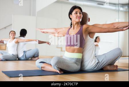 Woman practicing yoga with partner at studio Stock Photo