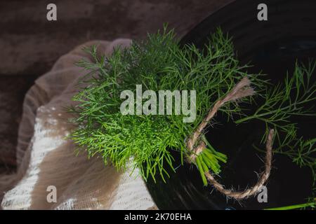 A bunch of fresh green dill on the table in a black aesthetic pl Stock Photo